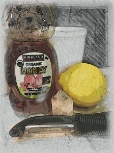 honey jar shaped like a bear. A lemon, a piece of ginger, and vegetable peeler are next to the jar