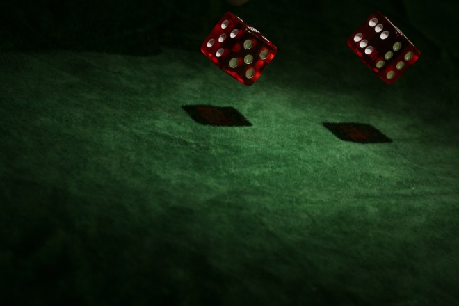 two red dice rolling on a green felt table