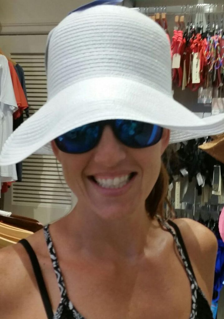 Smiling Caucasian woman in a big floppy white hat and sunglasses