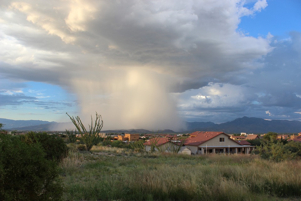 a storm cloud and falling rain onto a small desert town