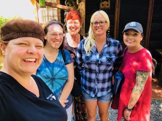 Group photo of 5 women in front of a cabin