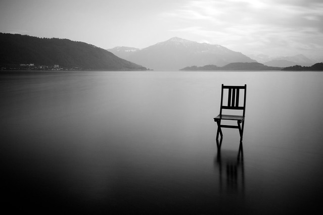 Folding chair atop a quiet lake in the mountains